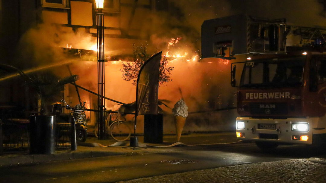 In-der-Nacht-Flammen-schlagen-aus-einem-Caf-Bl-mchen-